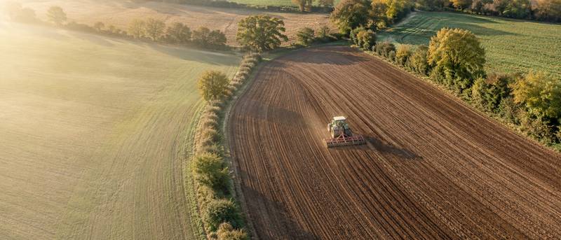 Vue aérienne d’un tracteur travaillant une parcelle entourée de haies